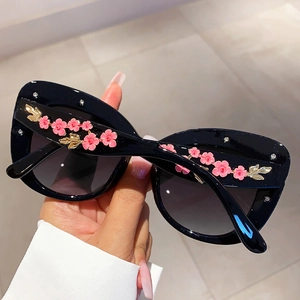 Detail of cat eye sunglasses with pink 3D flower petals and small gold metal leaves