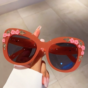 Detail of floral embellishments with pink enamel flowers on red cat eye sunglasses