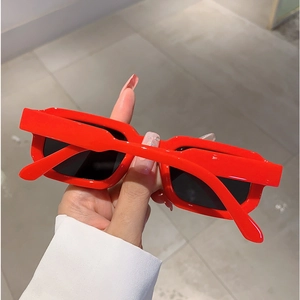 Lunettes de soleil rétro avec monture rouge épaisse et verres noirs en vue à la main