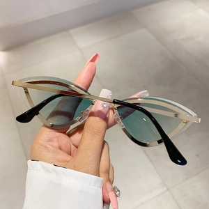 Handheld shot of cat-eye sunglasses with gold metal frames and green lenses