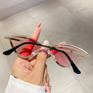 Macro detail of rimless cat-eye sunglasses with pink gradient lenses and gold metal trim