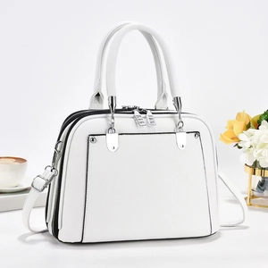 Detailed view of white lychee leather tote bag with black edge trim and silver hardware