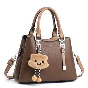 Close-up of dark brown leather handbag with contrast straps and plush cartoon charm
