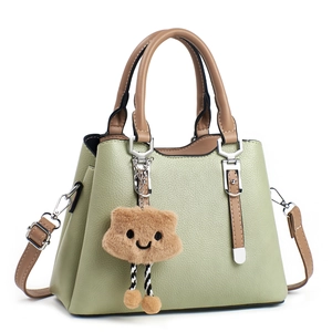 Chic light green lychee leather handbag with brown handles and plush cloud charm