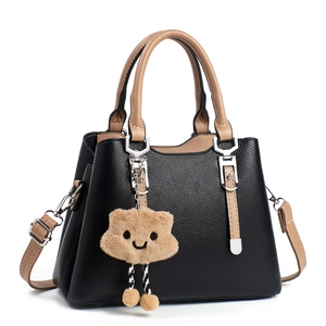 Black pebble leather handbag with khaki handles and a plush smiley cloud charm charm