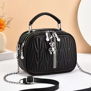 Detail of black quilted shoulder bag with silver bear charm and wavy stitch pattern