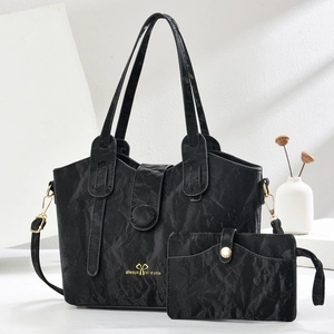 Detail of black wrinkled leather tote and clutch set with gold script and bow pattern