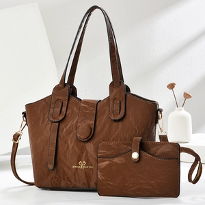 Detail of brown tote bag with wrinkled texture, gold buckles, and mini zipper pouch set