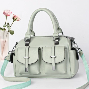 Detail of light green litchi grain leather handbag with T-buckle pockets and striped strap