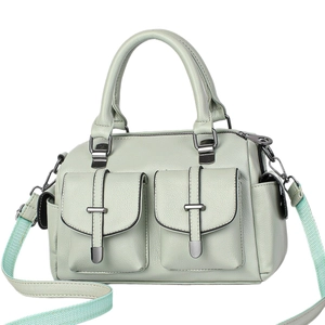 Light green faux leather handbag with twin front pockets and jacquard strap on white background