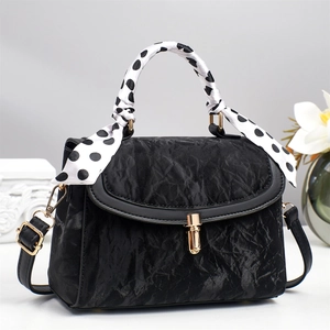 Close-up of black pleated texture bag with golden lock and polka dot scarf handle