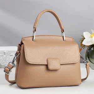 Khaki minimalist crossbody bag with lychee grain leather and round handle on gray background