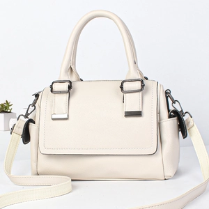 Minimalist cream leather Boston bag with side pockets and wide shoulder strap in studio shot
