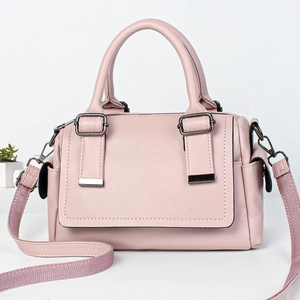 Close-up of light pink Boston bag with pebble leather texture and woven shoulder strap