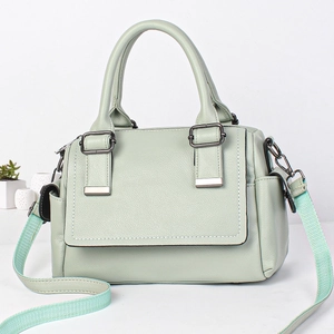 Detail of mint green leather bag showing wide fabric strap and textured grain surface
