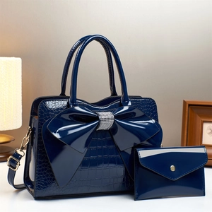 Detail of navy blue embossed patent leather handbag with sparkling rhinestone bow