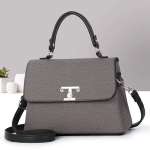 Dettaglio della borsa in tessuto grigio con finiture in pelle nera e chiusura in metallo argento