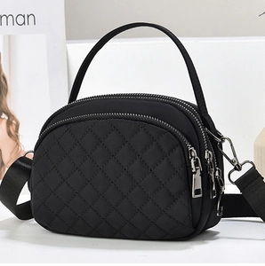 Detail of black quilted nylon crossbody bag featuring a triple zipper compartment design