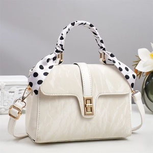 Detail of cream white marble texture handbag with gold lock and polka dot scarf handle
