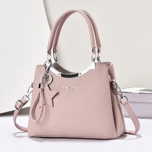 Detail of light pink crossbody bag featuring pebble leather texture and silver hardware