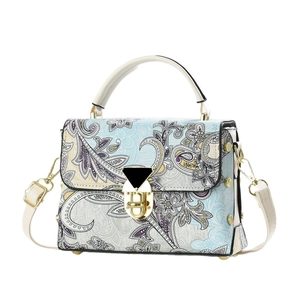 Floral paisley crossbody handbag with cream handles and gold hardware on white background