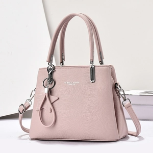 Close-up of pink lychee leather handbag with silver hardware and star charm detail