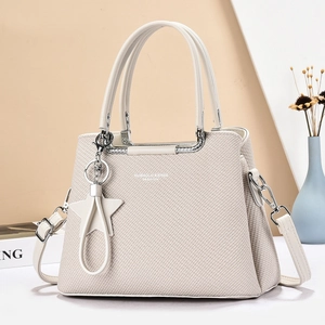 Détail du sac à main beige tressé avec finitions argentées et charm en étoile