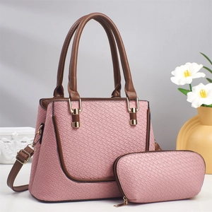 Détail du sac à main rose à texture tressée avec anses brunes et finitions dorées