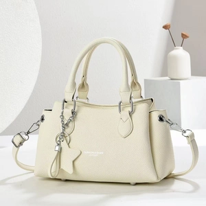 Chic off-white lychee leather Boston handbag with star charm and adjustable shoulder strap