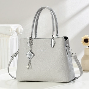 Sac à main minimaliste en cuir gris avec nœud en métal tressé et breloque en perle