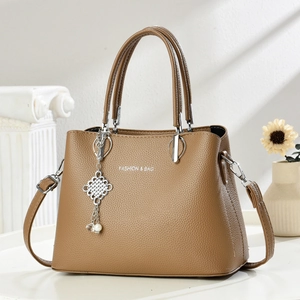 Sac à bandoulière minimaliste en cuir grainé marron avec pompons et détails argentés