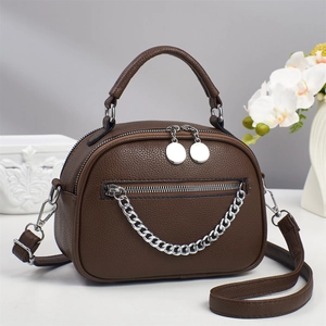 Detailed view of dark brown litchi leather bag with silver chain and dual zippers