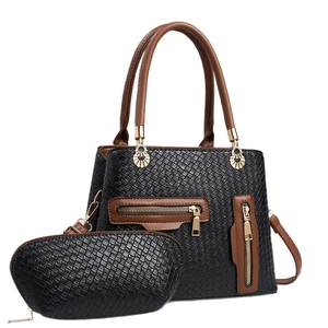 Black and brown woven leather tote bag set with golden floral charm on white background