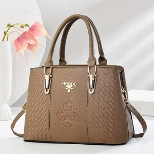 Close-up of brown pebbled leather handbag featuring embossed patterns and gold hardware