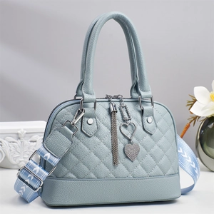 Detail of light blue quilted handbag with heart charm and woven wide shoulder strap