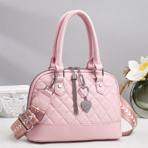 Detailed view of pink quilted shell bag featuring rhinestone heart tassel and wide strap