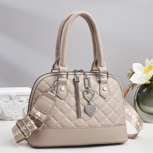 Close-up of beige shell handbag with quilted pattern, heart charm and jacquard strap