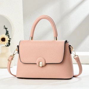 Dettaglio della borsa in pelle rosa con chiusura a rotazione dorata e manico circolare