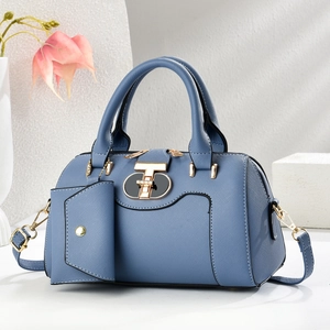 Blue large capacity Boston handbag with crossbody strap and small charm on stone pedestal