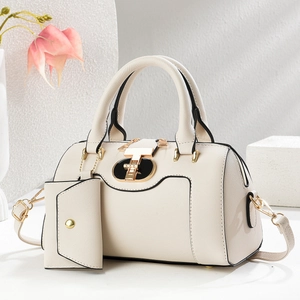 Close-up of cream handbag with golden buckle and matching mini wallet on a white stand