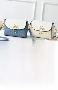 Detail of crossbody bag featuring golden swan buckle and elegant pearl tassel accessory