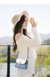 Detail of crossbody bag featuring heart-shaped gold lock and tassel with diamond pattern