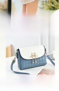 Detail of blue and white square crossbody bag with gold swan clasp and pearl tassel