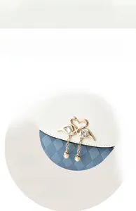 Detail of gold swan hardware with crystals and pearls on white and blue woven bag