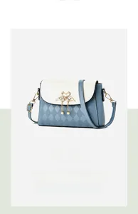 Detail of color-block flap bag with quilted pattern, swan metal clasp, and pearl charms