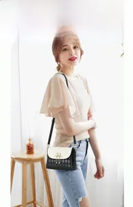 Detail view of mini quilted crossbody bag with gold swan buckle and tassel accents