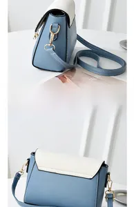 Detail showing the light blue contrast stitching, side view, and pearl charm of this bag