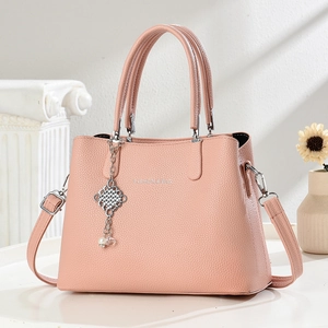 Minimalist pink pebble leather handbag for women featuring a pearl charm and shoulder strap