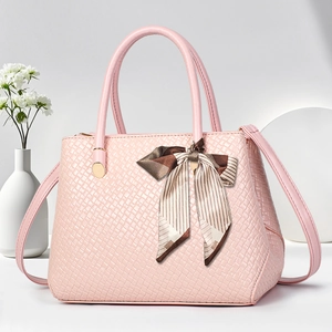 Detail of pink woven texture handbag with a striped silk scarf bow and gold hardware