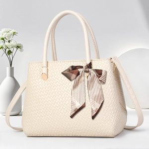 Detail of cream white woven handbag featuring a decorative silk scarf on the handle